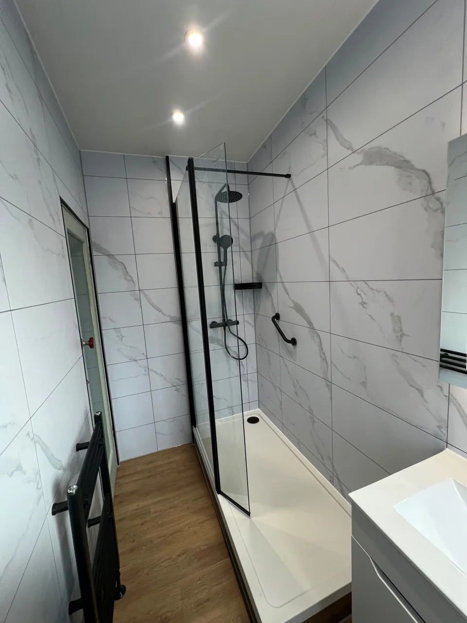 Narrow shower room with black fittings and wood-effect floor