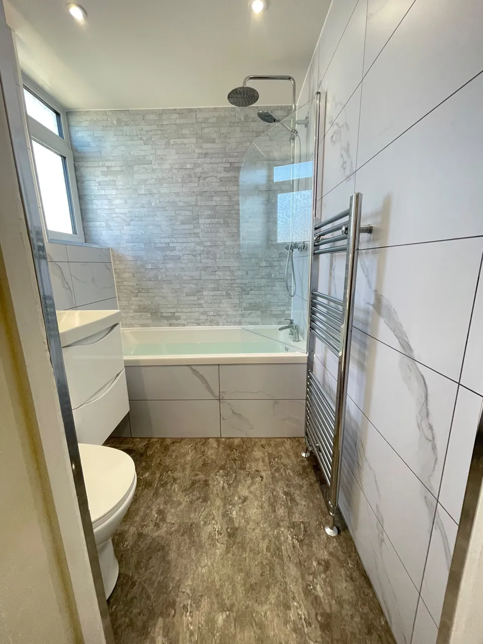White fitted bath and vanity with marble-effect walls