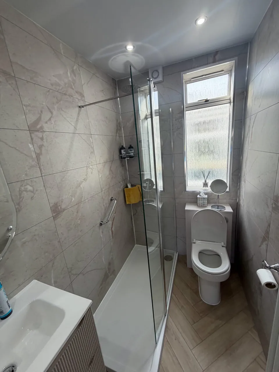 Narrow marble-effect shower room with white bathroom furniture